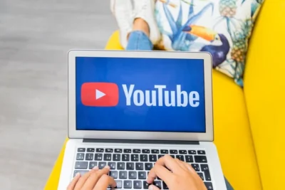 Imagem mostrando uma pessoa digitando em um laptop com o logotipo do YouTube na tela, ideal para entender sobre anúncios no YouTube e marketing digital.