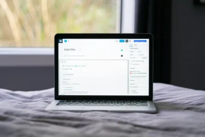Imagem de um laptop aberto sobre uma cama, exibindo uma tela de edição com a opção para adicionar um título, perfeita para otimização de title tags.