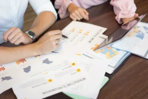 Pessoa analisando documentos de planejamento de negócios e gráficos, aprendendo Como Criar um Plano de Negócios Sólido em 7 Passos para o sucesso empresarial.