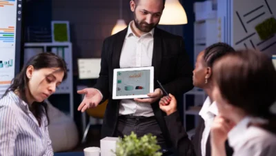 Profissional explica estratégias para transformar um negócio tradicional em uma plataforma digital lucrativa durante uma reunião de equipe.